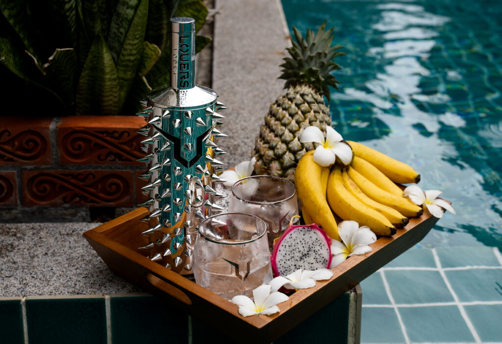 Butelka wódki LOUERS na basenie w pobliżu tropikalnych owoców