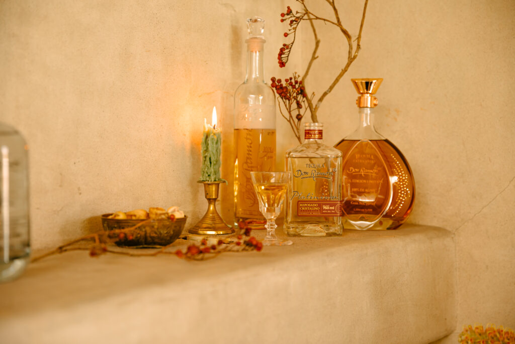 Casa Don Ramon tequila bottles on wall with candle and flowers