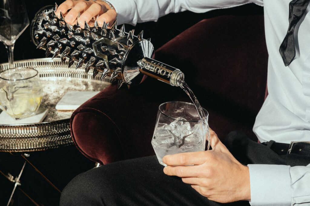 Elegantly dressed man pours LOUERS vodka into a glass with ice