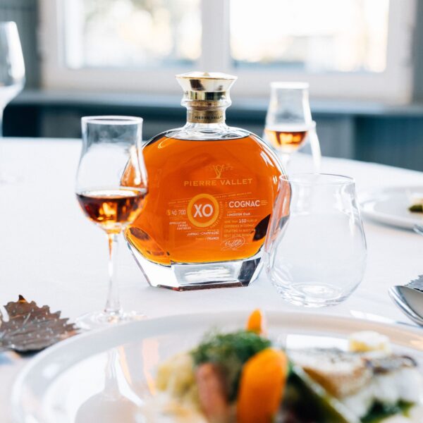 Butelka francuskiego koniaku Pierre Vallet XO Cognac przy zastawie stołowej