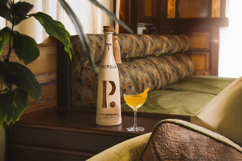 a bottle of the best gin Palmaráe and a citrus-garnished cocktail in an elegant interior setting
