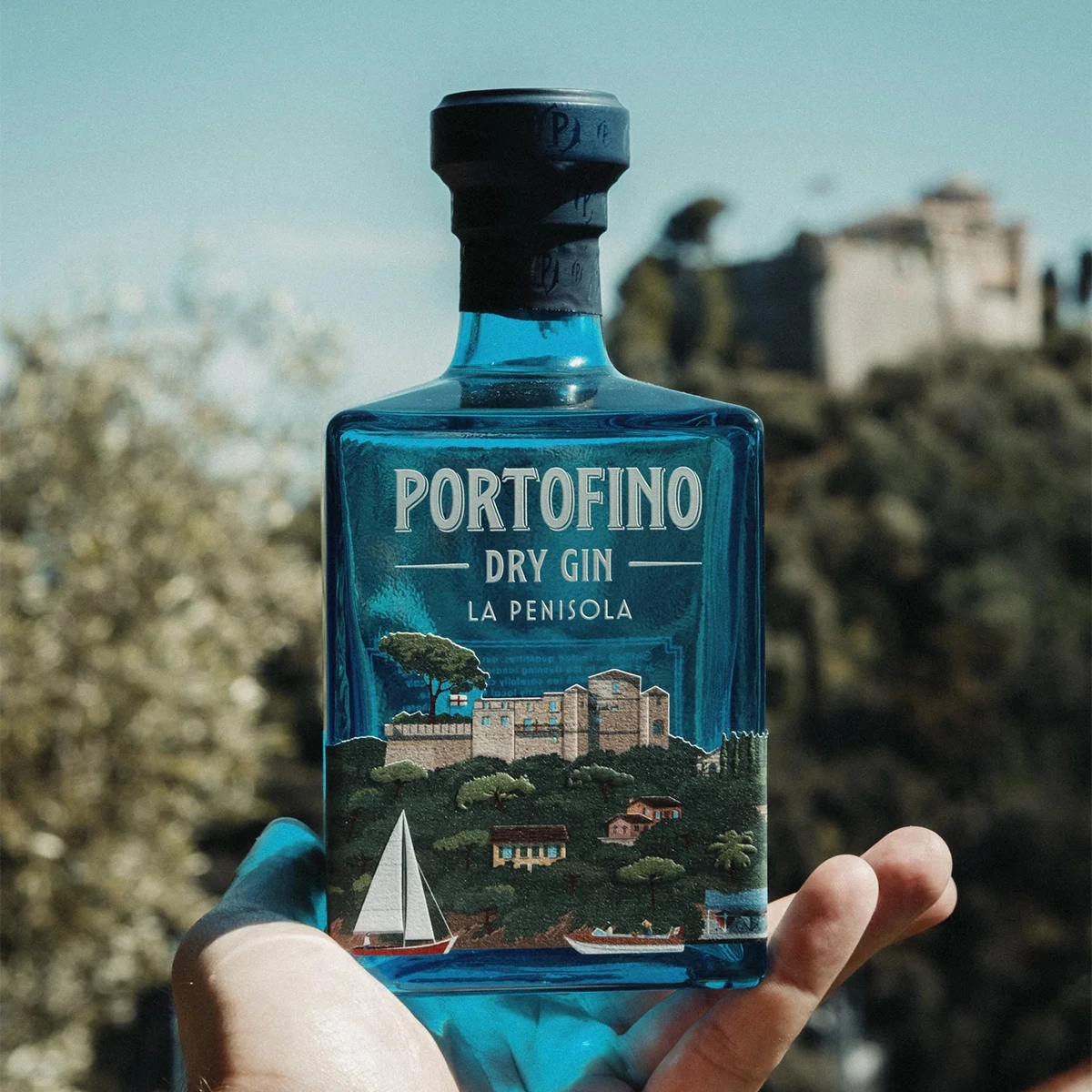 A hand holding a bottle of Portofino Dry Gin La Penisola