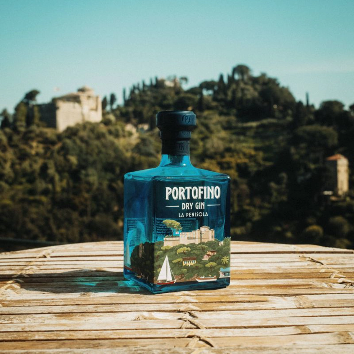 A bottle of Portofino Dry Gin La Penisola against an Italian landscape.